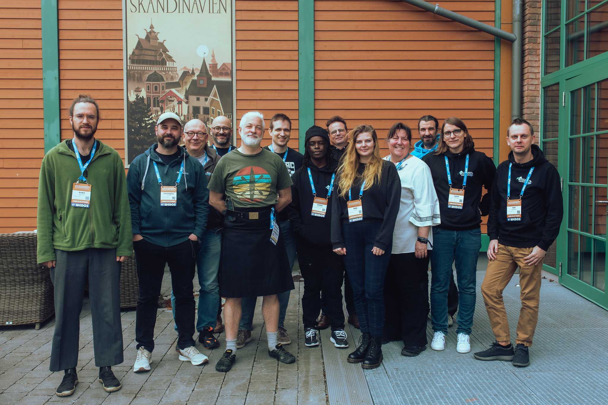 Group picture of 13 people. 9 men and 4 women. Most people wear hoodies and all have Badges.